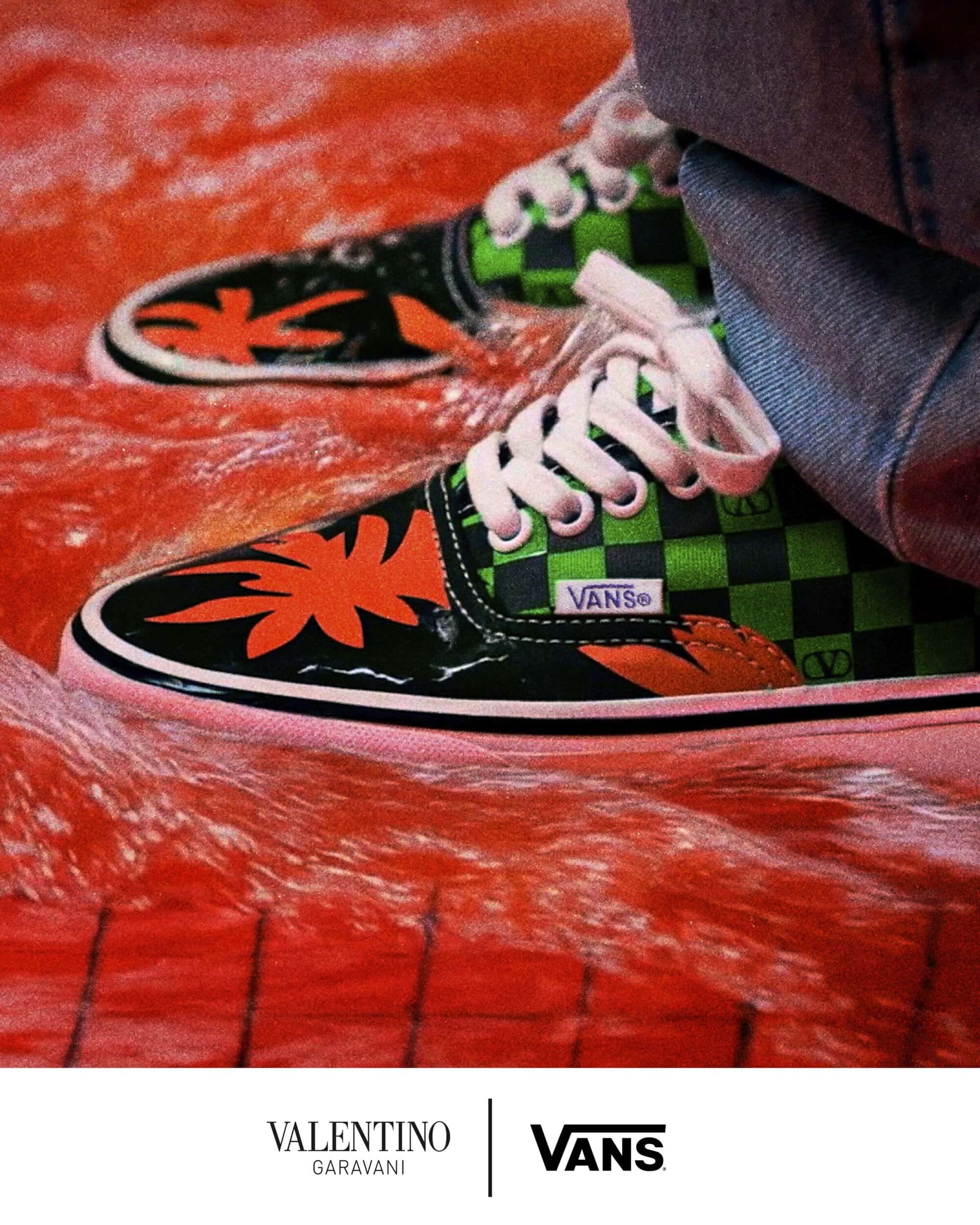 Close-up of checkered green and black sneakers with orange floral details standing in swirling red water.