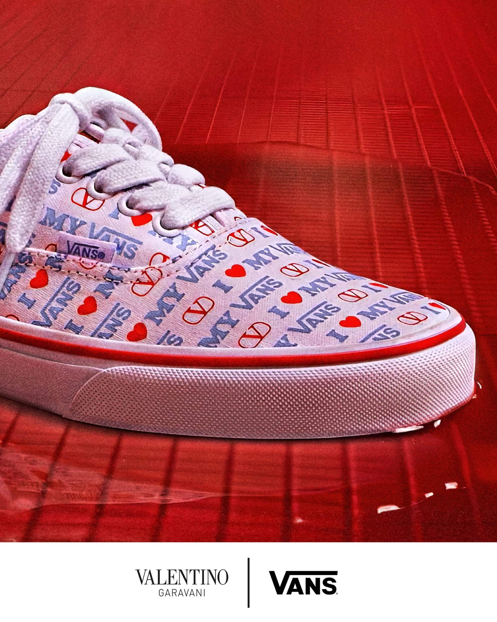 Close-up of a white patterned sneaker with red and blue typography resting on a glossy red surface.