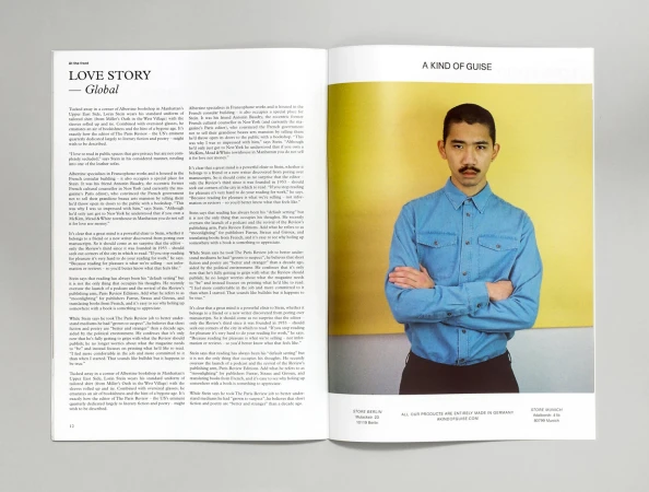 Open magazine spread showing text on the left and a man in a blue shirt with crossed arms against a yellow and grey wall on the right.