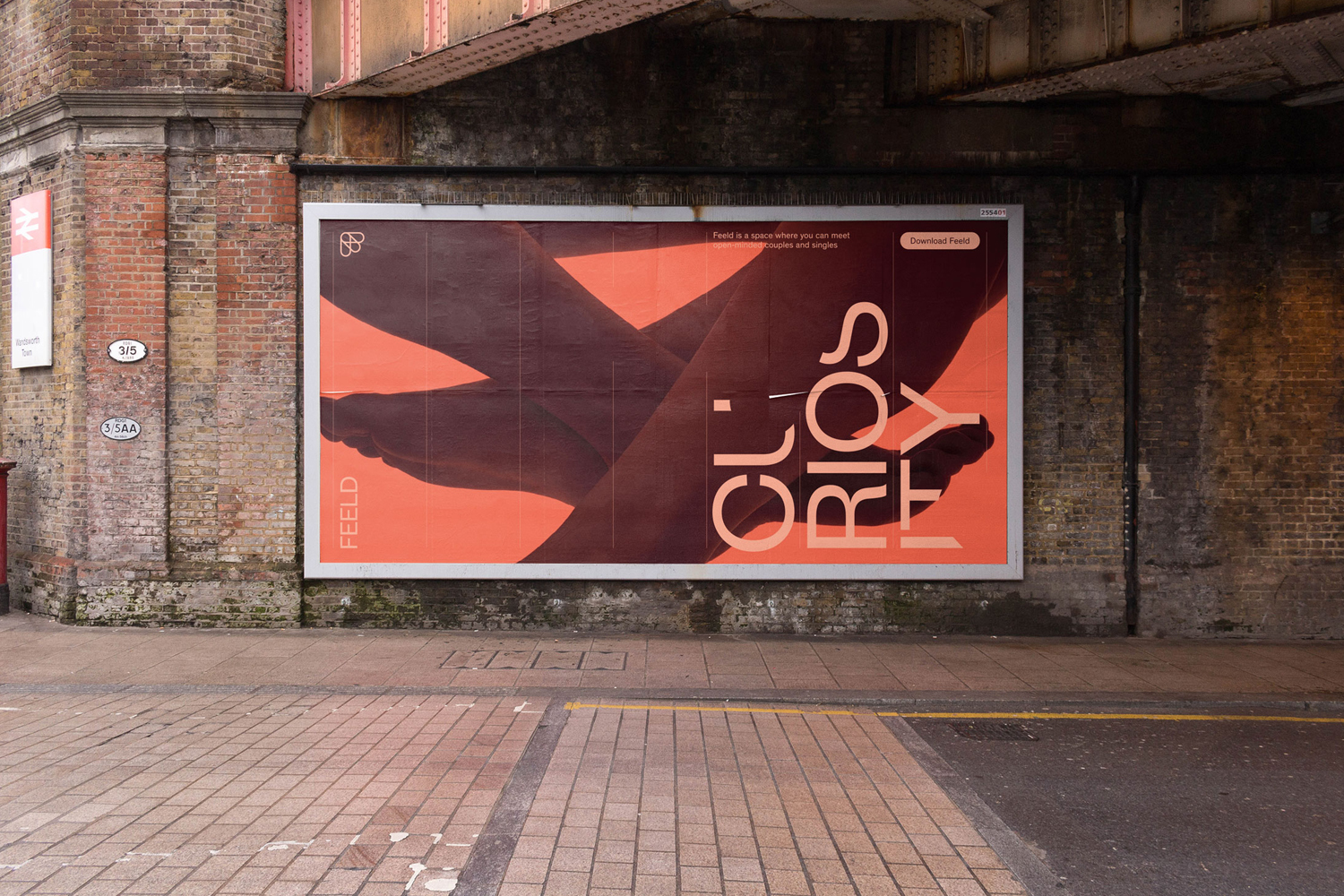 Large Feeld brand identity billboard poster mounted on a weathered brick wall beneath a railway bridge.