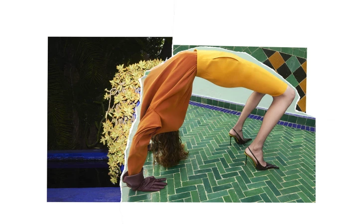 Model bending backwards in a backbend pose wearing an orange top, yellow skirt, and dark high heels on a green tiled patio