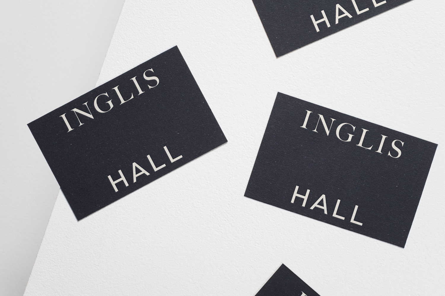 Black business cards featuring Inglis Hall branding arranged on a white textured background.