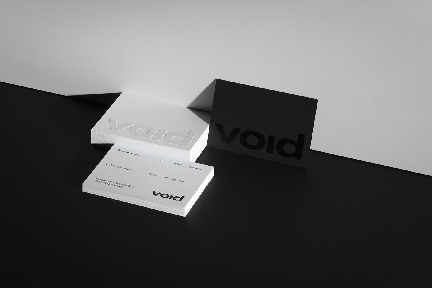 Monochrome product shot of stacked white and black business cards featuring the brand name Void on a stark angled background