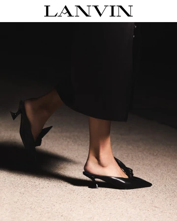 Close-up of a person walking wearing black leather pointed-toe mules and a dark skirt for a Lanvin editorial shoot.
