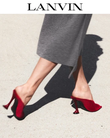 Close-up of a model wearing red mules and a grey skirt outdoors in bright sunlight, with the Lanvin logo above.
