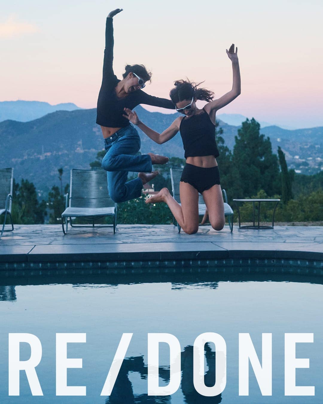 Two women leaping joyfully by a swimming pool at sunset for the RE/DONE Fall 2025 ad campaign.
