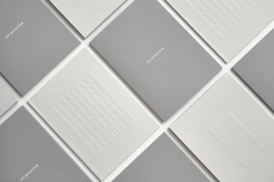 An arrangement of grey and white minimal booklets with embossed architectural details and 150 Wooster typography.