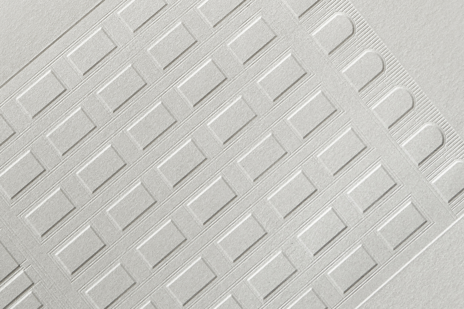 Close-up of a white textured paper with an embossed architectural grid and arched patterns designed by Javas Lehn Studio.