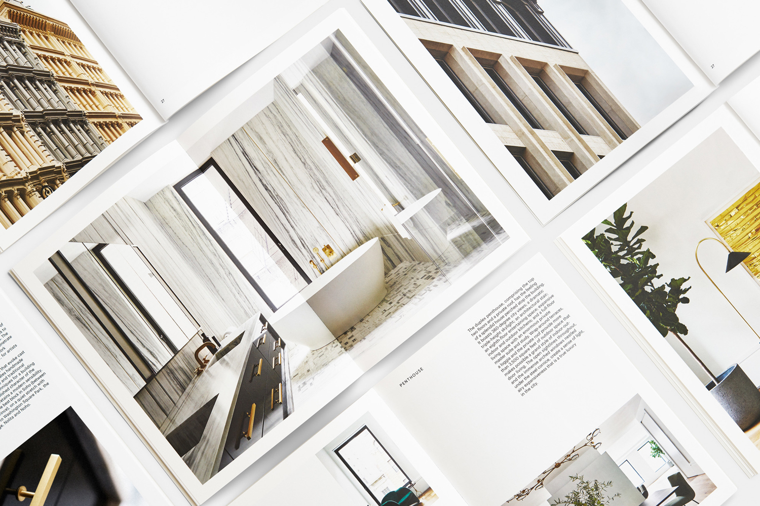 A flat lay photograph showing multiple open pages of a high-end real estate brochure featuring architectural photography and interior design.