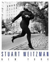 Ashley Graham walking on a New York sidewalk wearing a dark jacket and heeled boots for Stuart Weitzman campaign