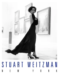 Ilana Glazer in a long black backless dress and heels posing inside a gallery for Stuart Weitzman Fall 2025 ad campaign