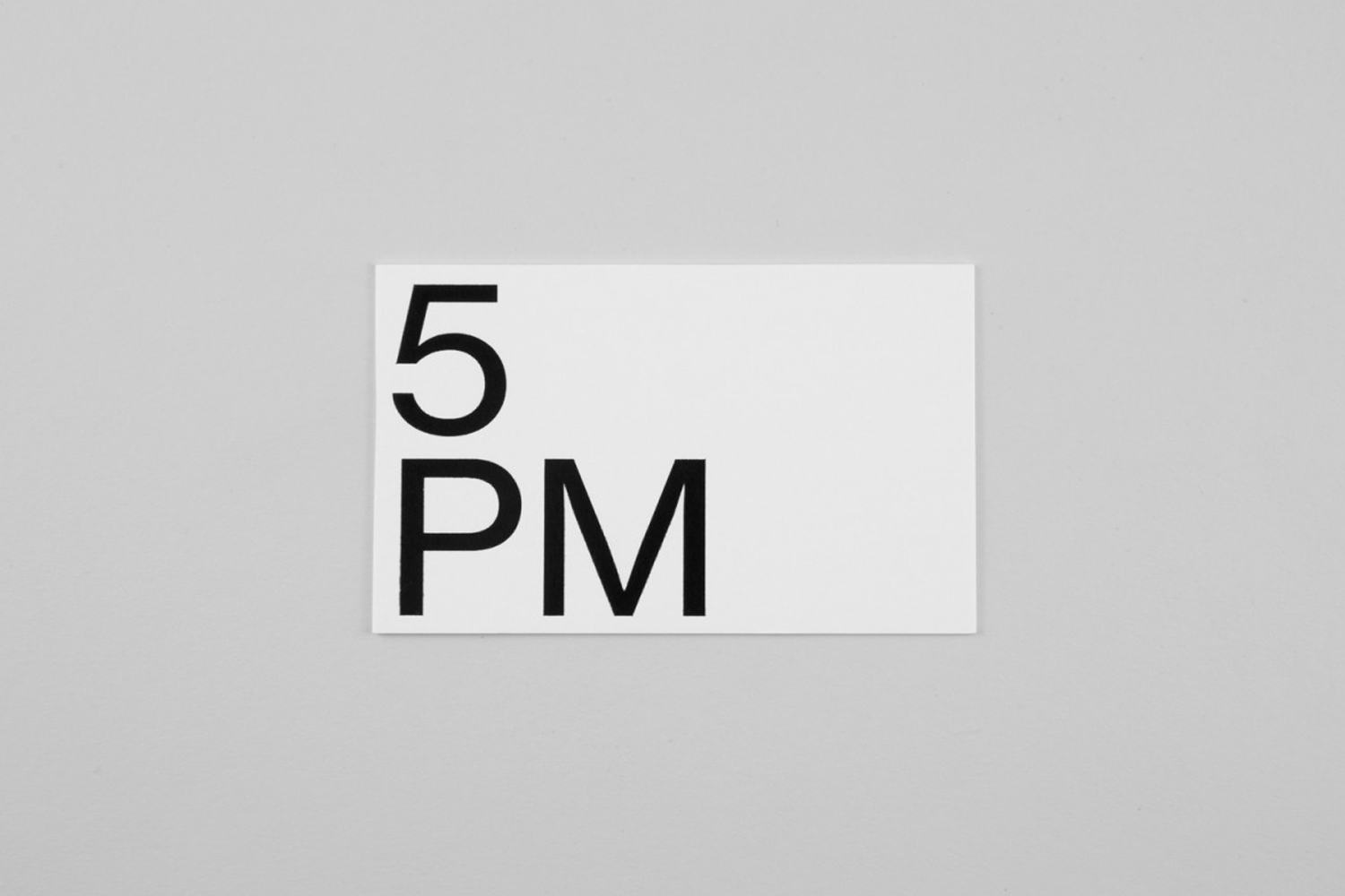 Minimalist graphic design identity card for 5PM featuring bold black typography on a white card against a neutral grey surface.