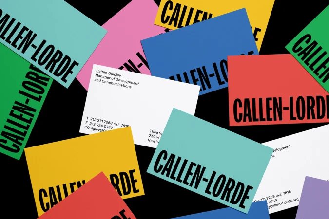 A flat lay of colorful Callen-Lorde brand identity stationery and business cards scattered on a black background