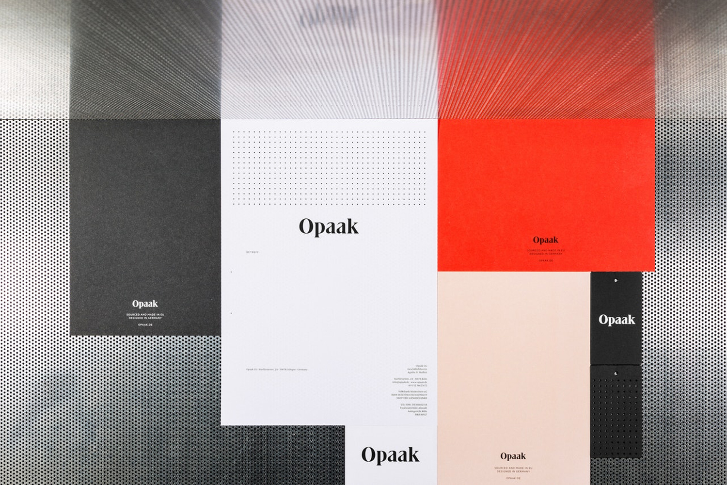Flat lay of corporate stationery branding materials featuring the Opaak logo on white, black, red, and peach paper against a perforated metal texture