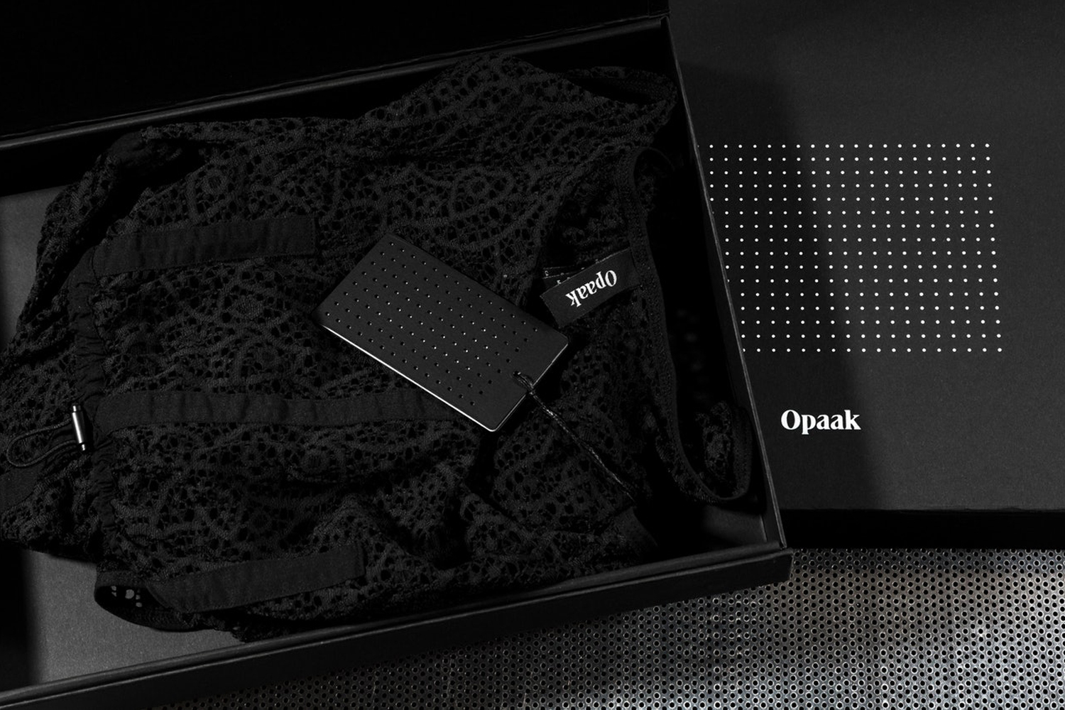 Black lace garment inside a black gift box with perforated brand tag by Deutsche und Japaner