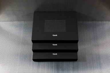 Three stacked matte black boxes featuring white typography and a dotted grid pattern against a textured metal background.