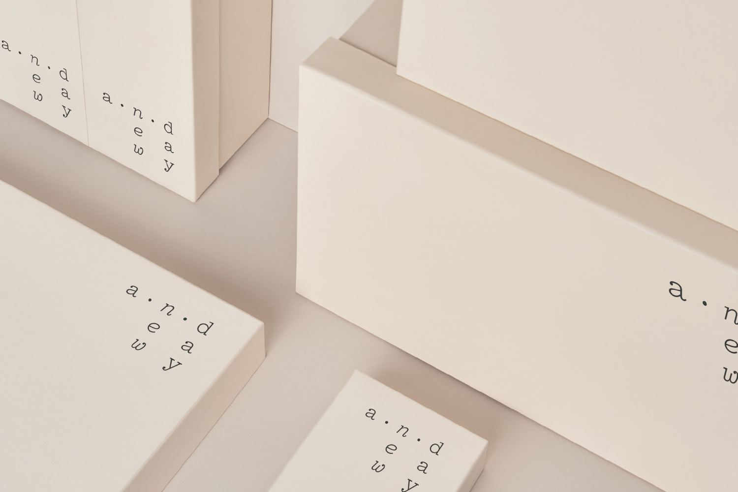 Close-up of minimalist cream-colored packaging boxes with typography branding on a neutral background