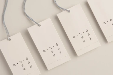 Four off-white paper swing tags featuring minimalist typography with blue string against a clean background