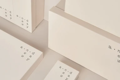 Close-up of minimalist cream-colored packaging boxes with typography branding on a neutral background