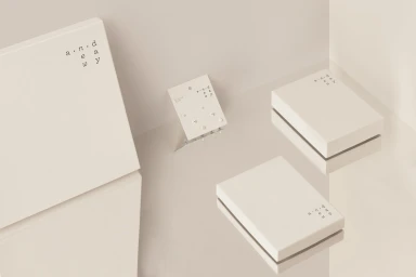 Minimalist product photography featuring white packaging boxes and an earring display card on a reflective surface.