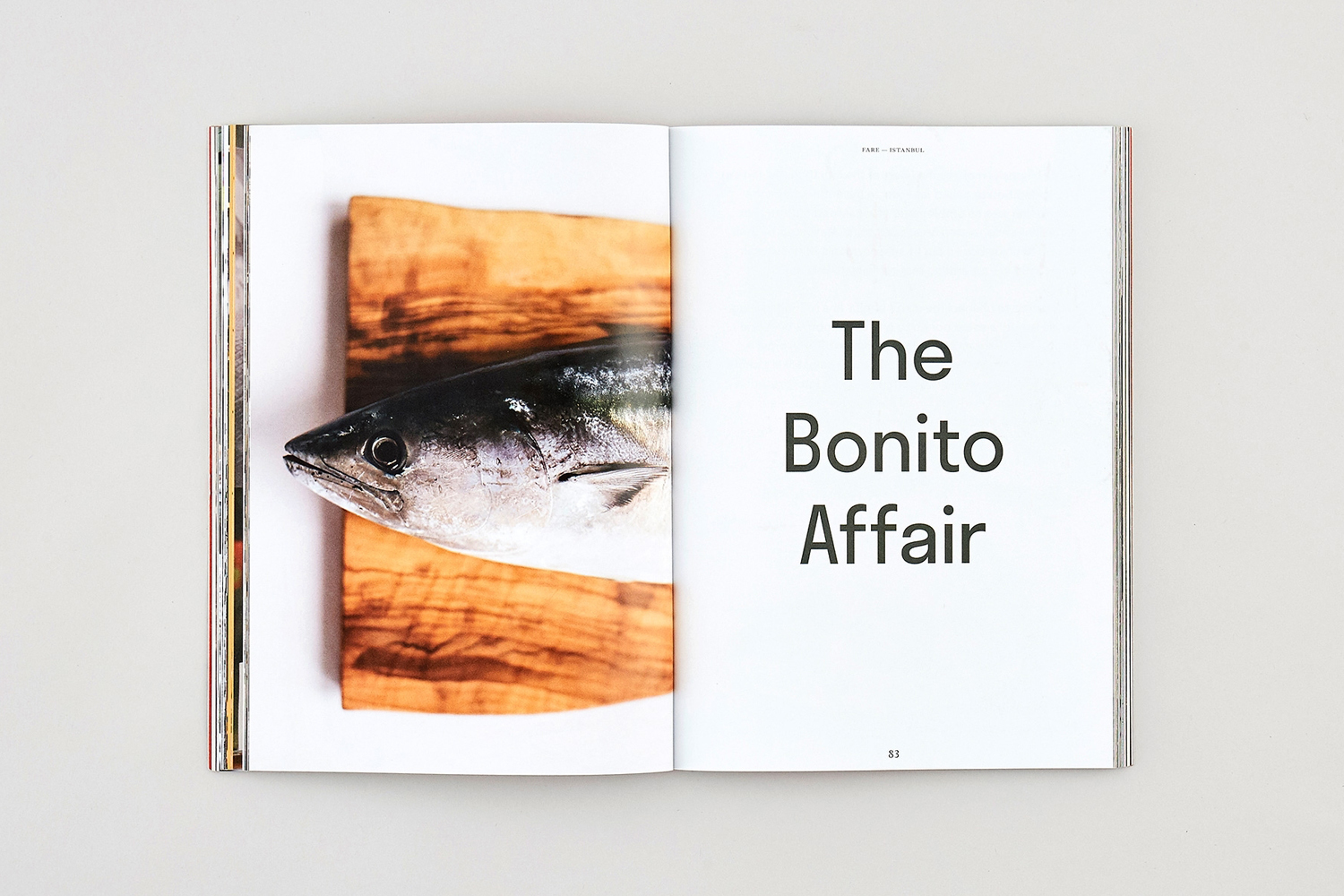 Open magazine spread showing a fresh fish on a wooden board on the left and typography reading The Bonito Affair on the right