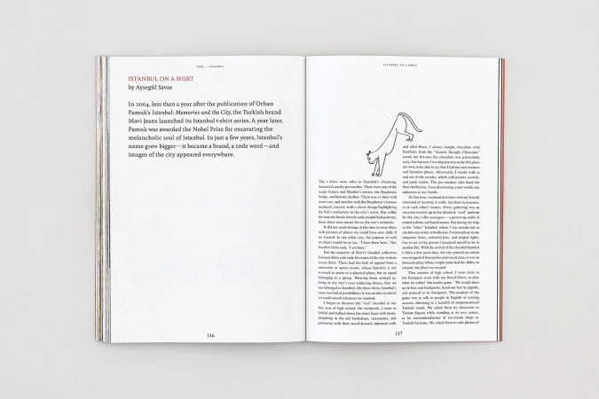 Open magazine spread on a neutral surface featuring typographic layout, printed text columns, and a line drawing of a cat.