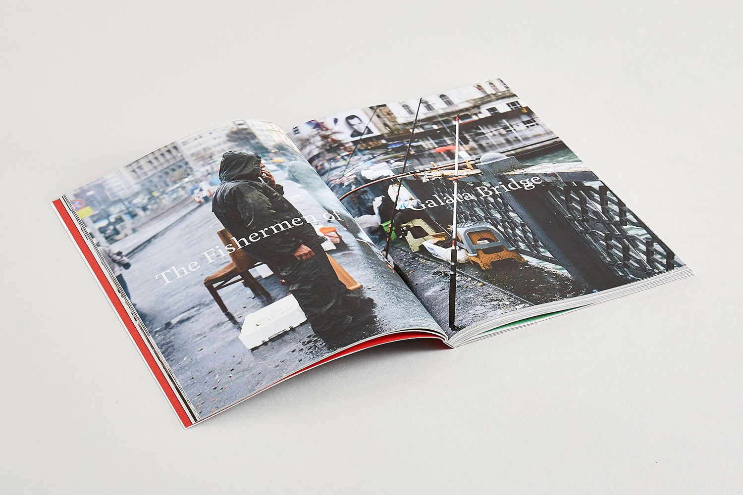 Open magazine spread on white surface featuring documentary photography of fishermen on a bridge