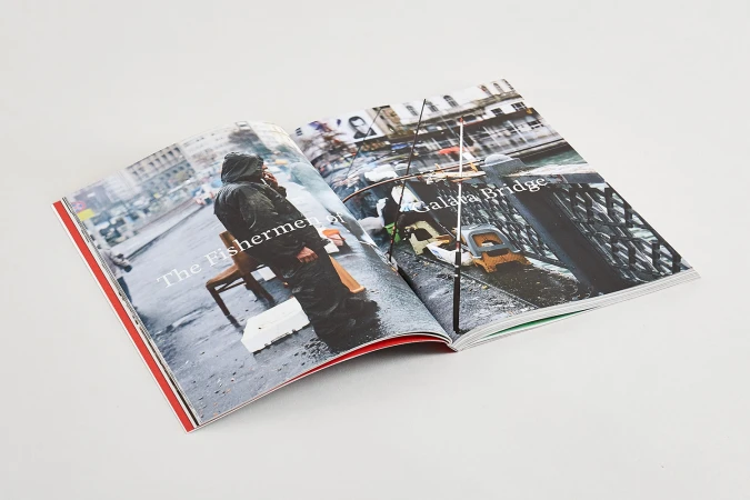 Open magazine spread on white surface featuring documentary photography of fishermen on a bridge