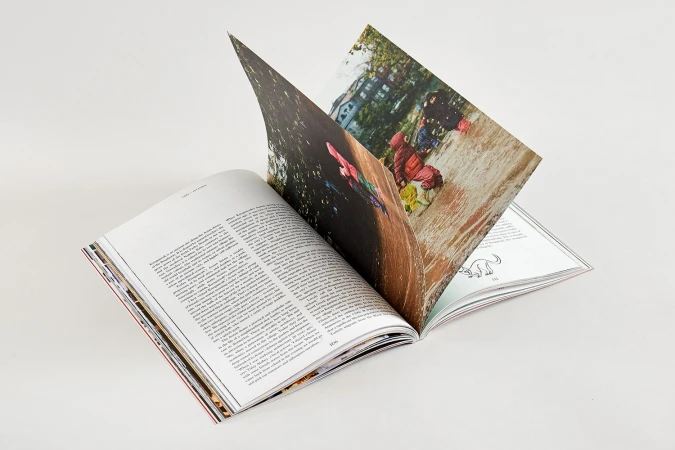 An open book with white pages and vibrant photographs is displayed on a clean white surface.