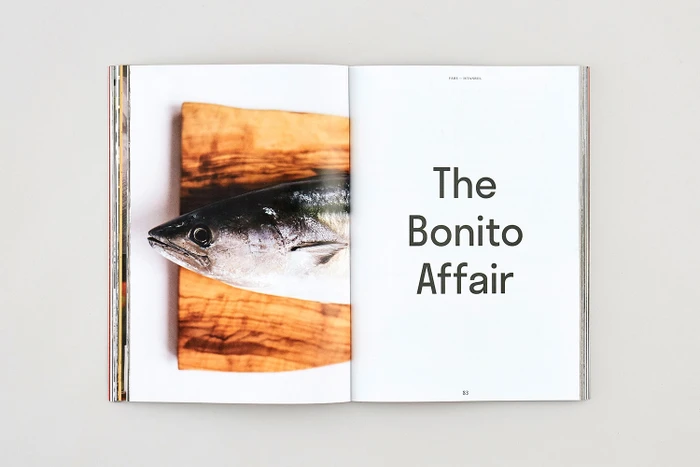 Open magazine spread showing a fresh fish on a wooden board on the left and typography reading The Bonito Affair on the right