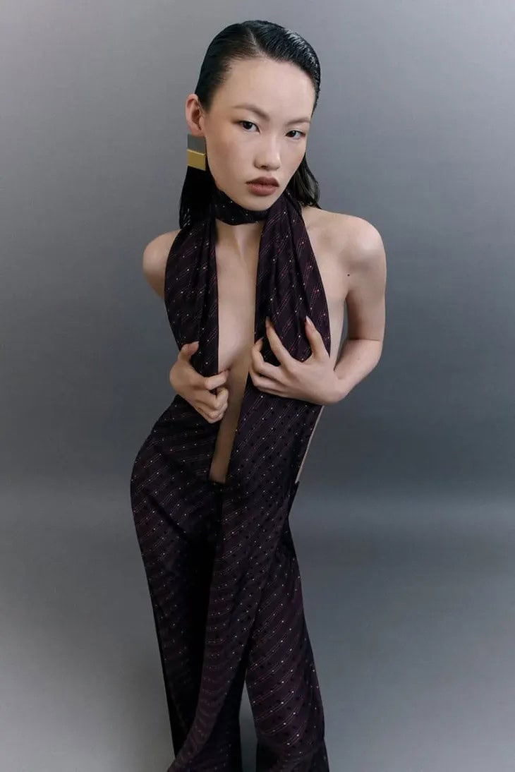 Model in patterned dark halterneck top against a grey seamless background for Acne Studios
