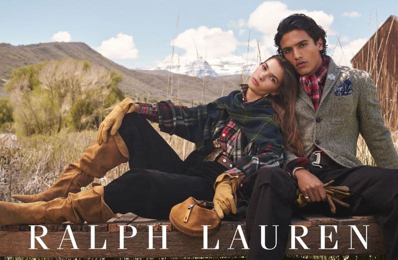 Two models posing outdoors on a wooden dock with mountain and sky backdrop for Ralph Lauren Fall 2025 campaign.