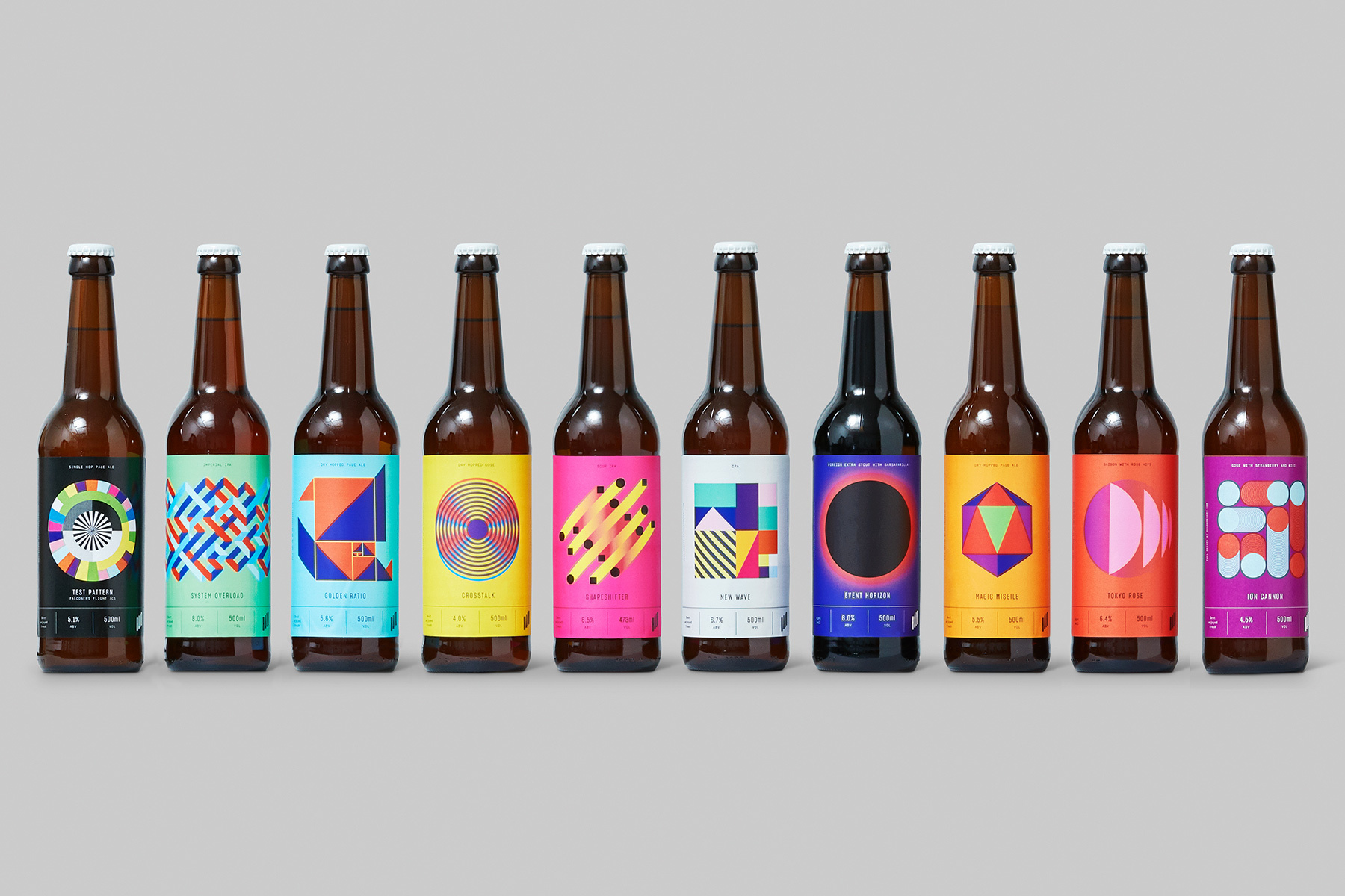 Ten brown glass beer bottles with colourful geometric patterned labels lined up on a grey seamless background