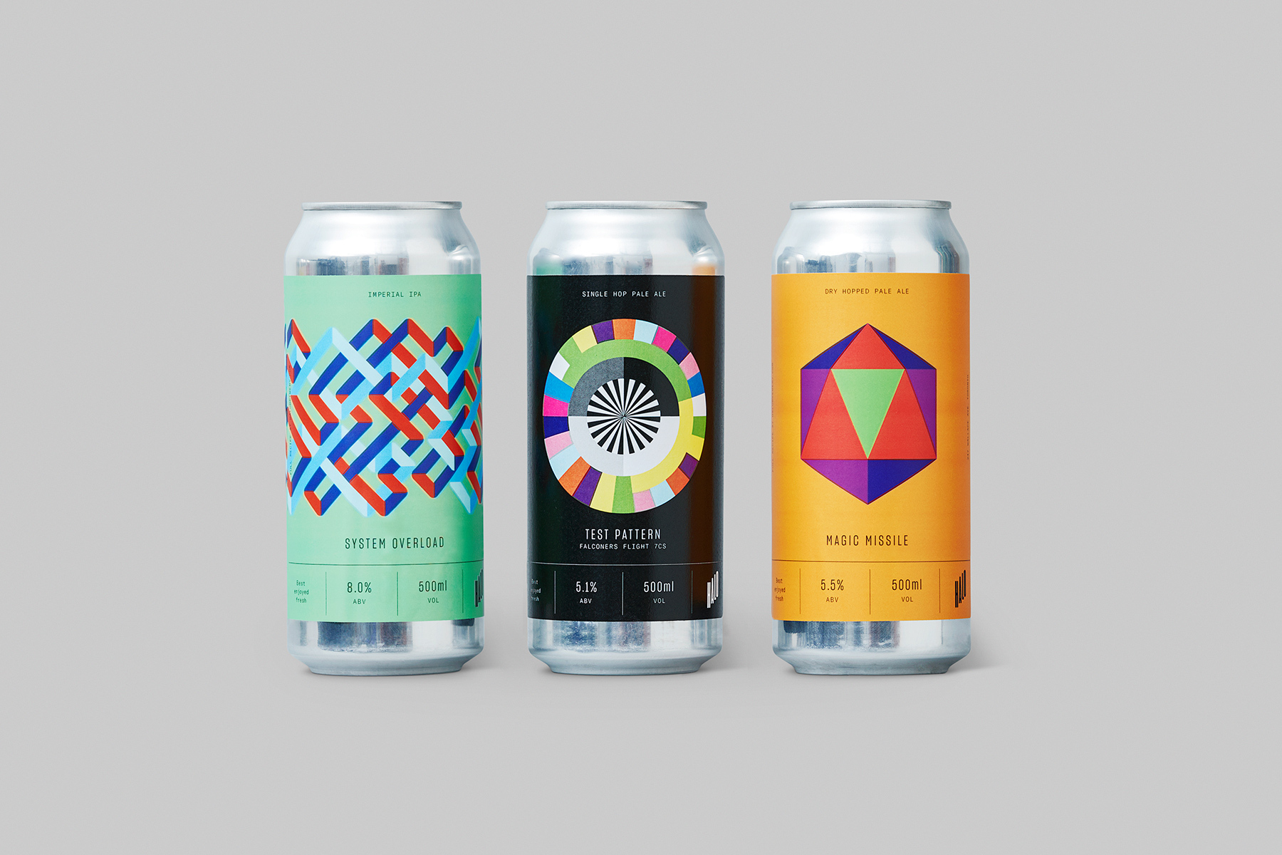 Three metal beverage cans with colorful geometric label designs standing upright against a plain grey studio background.