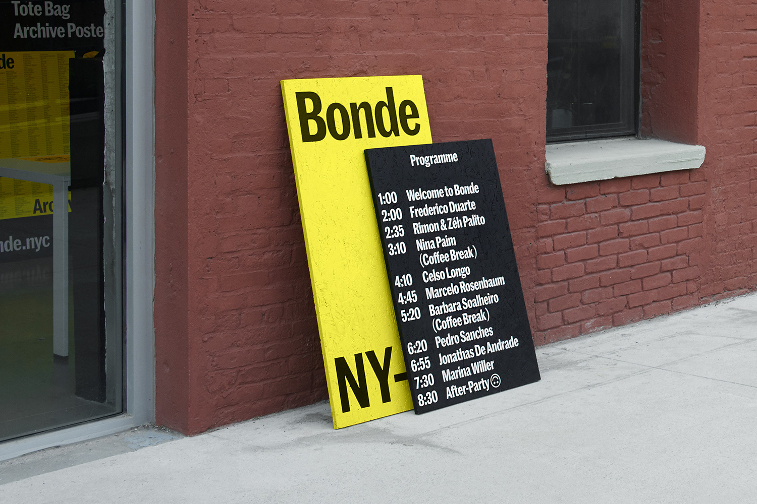 Yellow and black graphic design signs leaning against a red brick building exterior