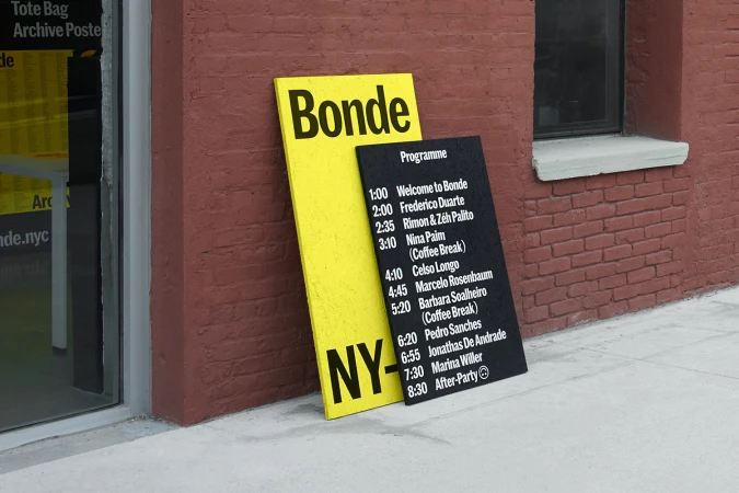 Yellow and black graphic design signs leaning against a red brick building exterior