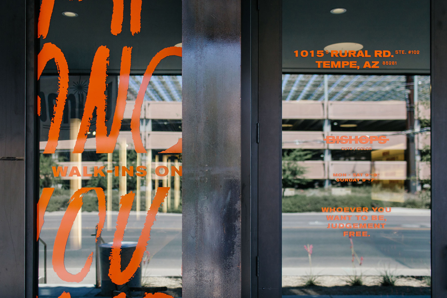 Glass storefront with bold orange custom typography on window graphics for Bishops brand identity project