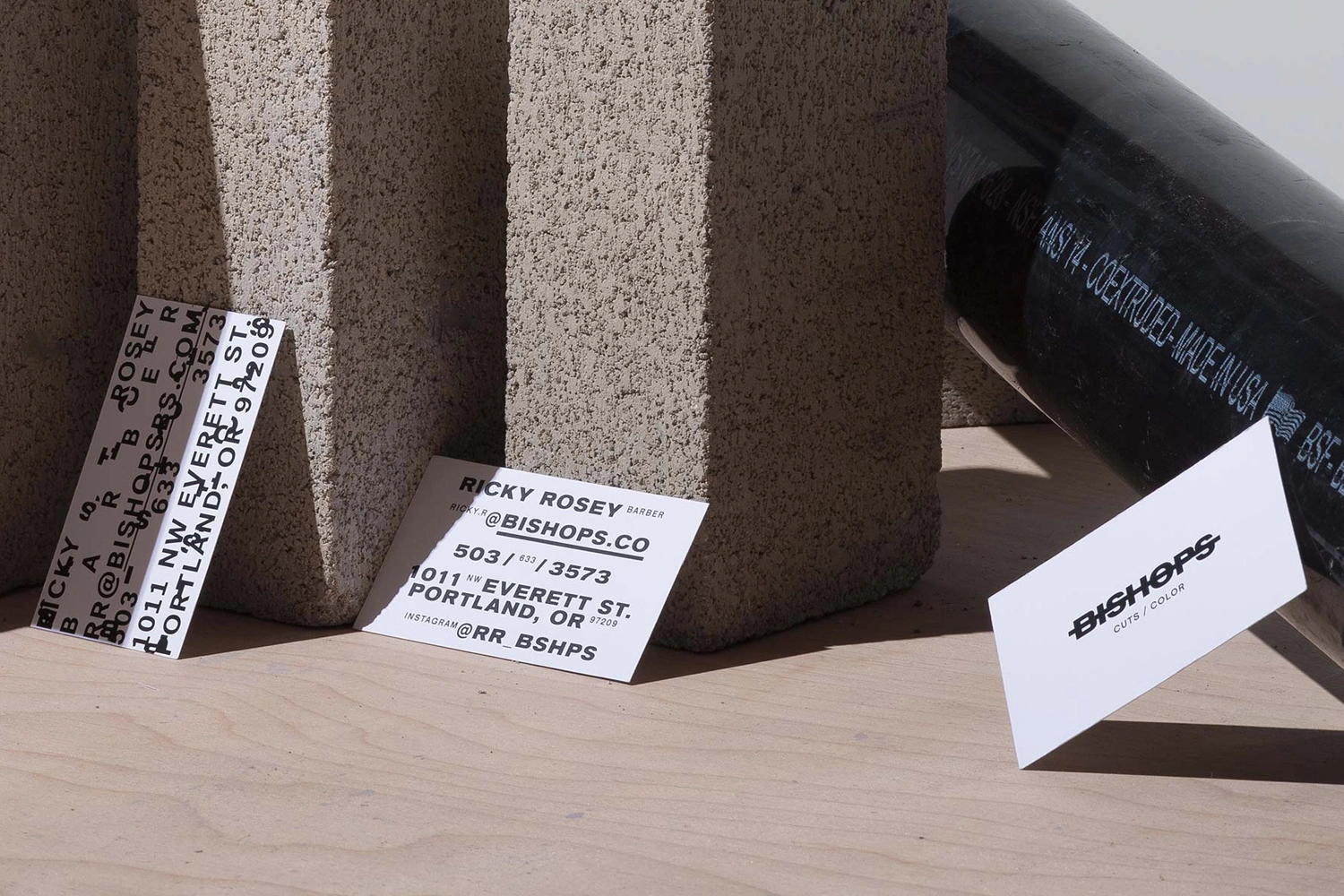 Bishops brand identity design featuring business cards and typography against concrete blocks and a dark pipe