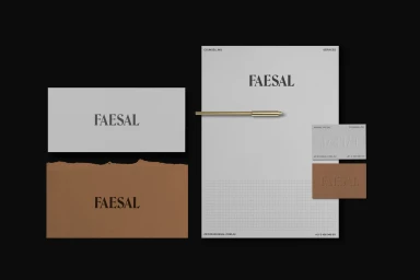 Faesal brand identity stationary mockup featuring letterhead, business cards, and a brass pen on dark background.