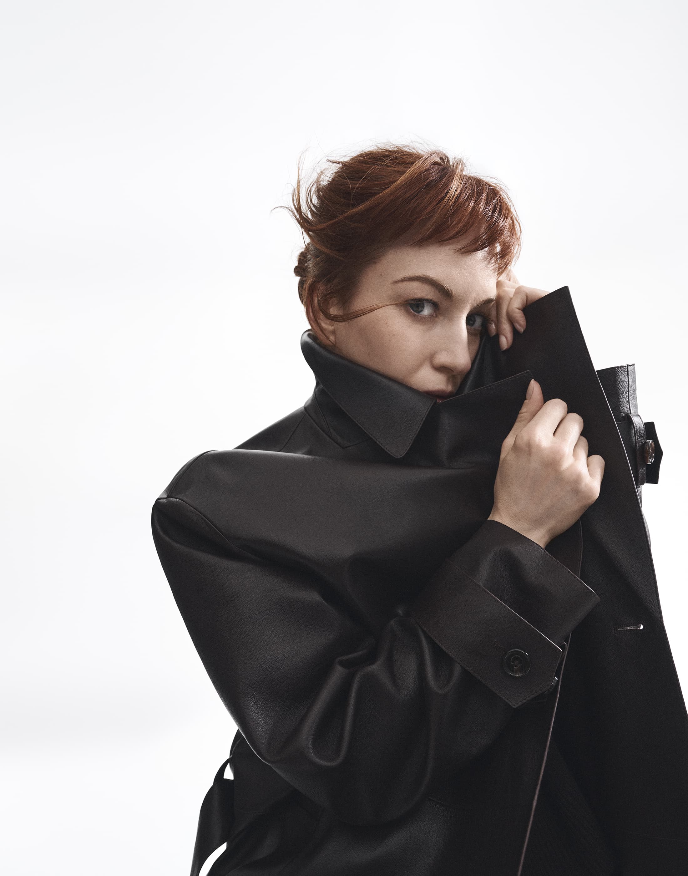 Britt Lower in a black leather coat with high collar pulled up, against a white seamless background for Theory