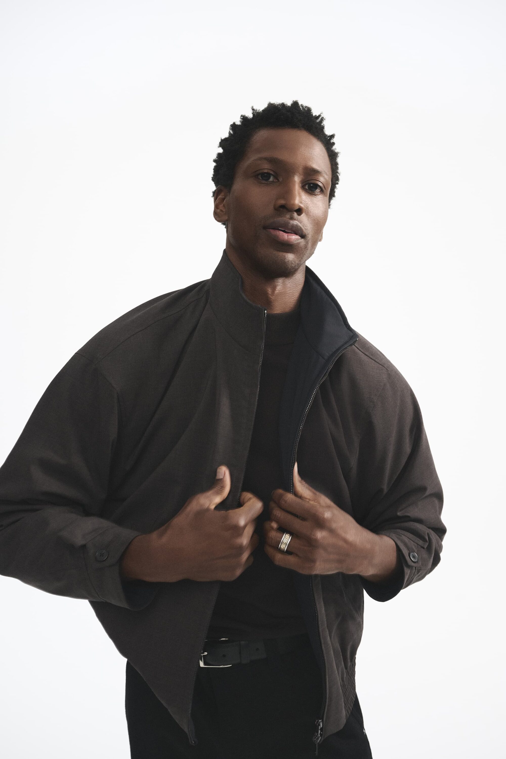 Man wearing a dark jacket standing against a plain white background for the Theory Fall 2025 campaign
