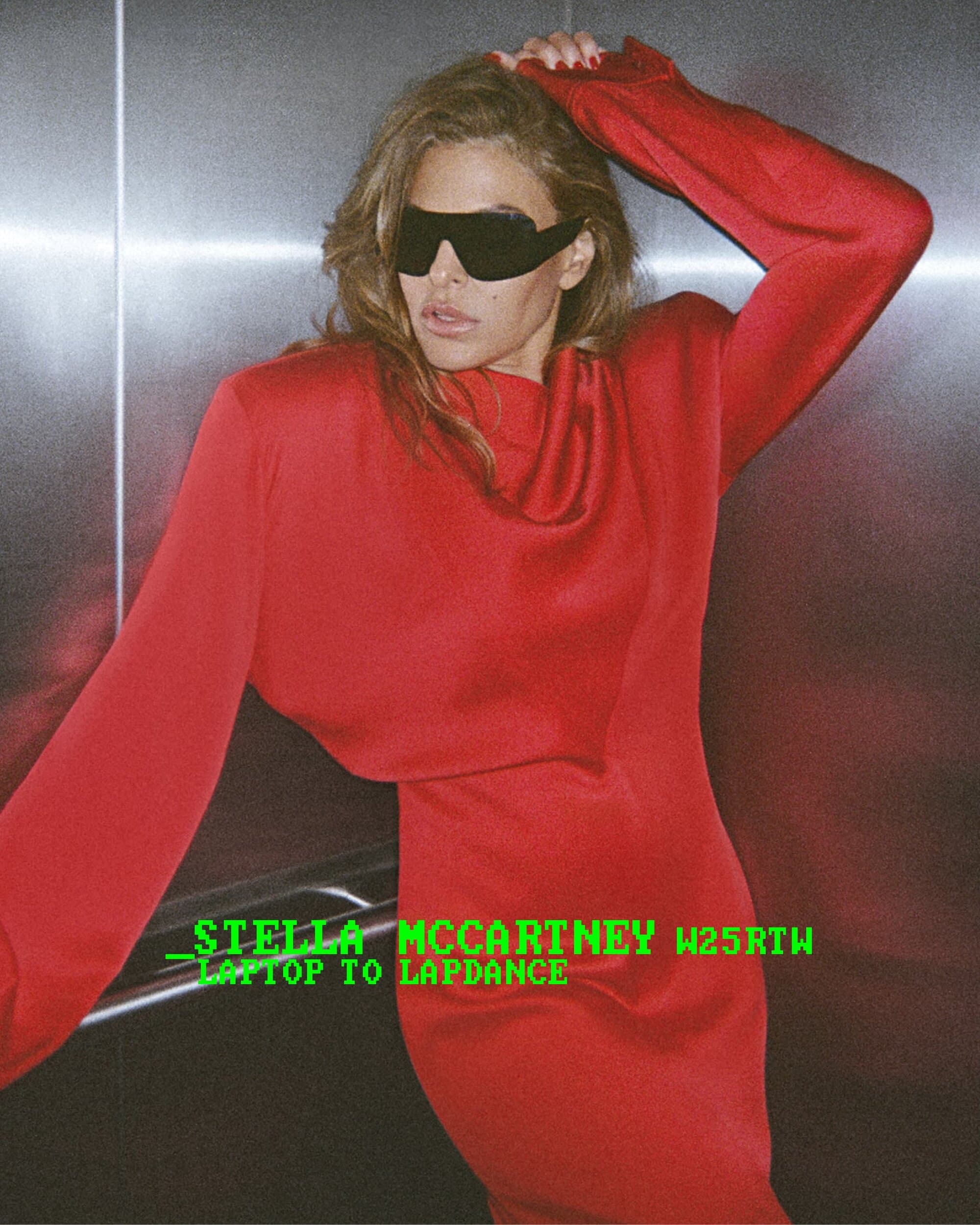 Model in red long-sleeve dress and black sunglasses posing against a metallic elevator wall for Stella McCartney