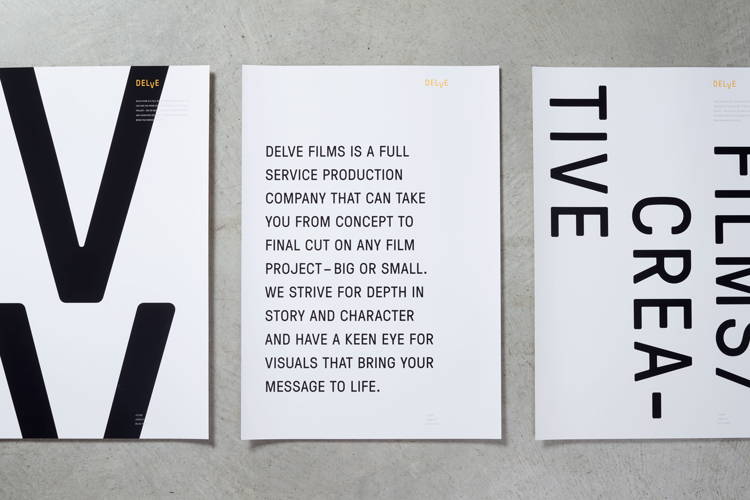 Three white posters with bold black typography arranged on a textured grey concrete surface.