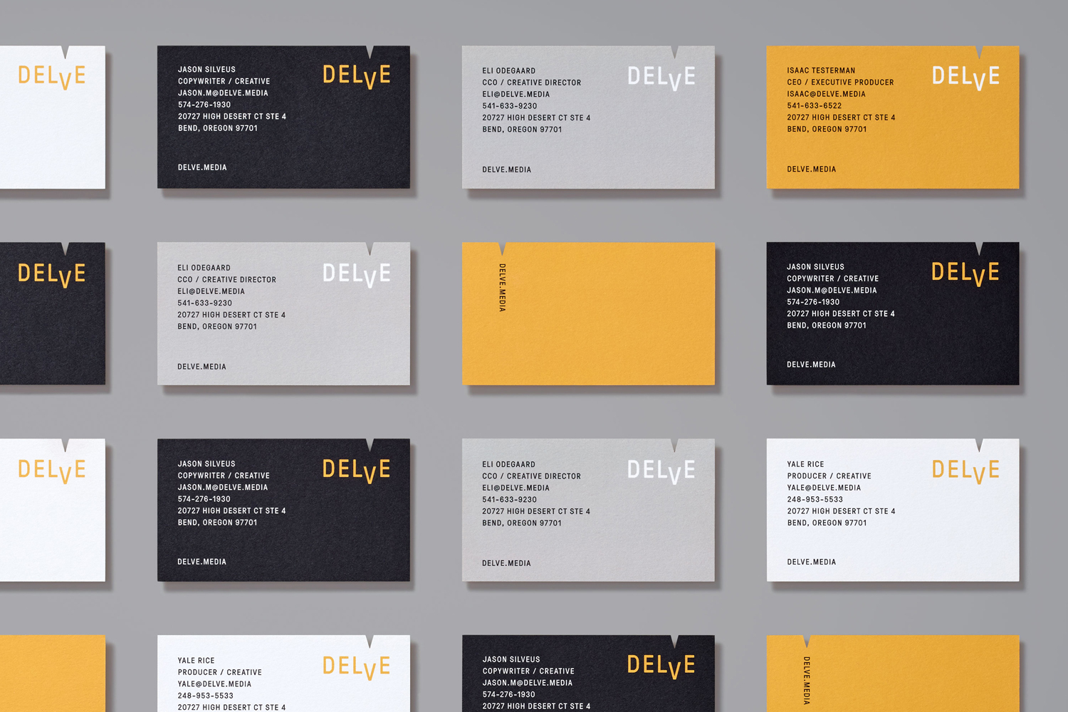 Multiple Delve business cards in white, black, grey, and yellow arranged in a grid on a grey surface.