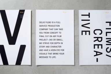 Three white posters with bold black typography arranged on a textured grey concrete surface.