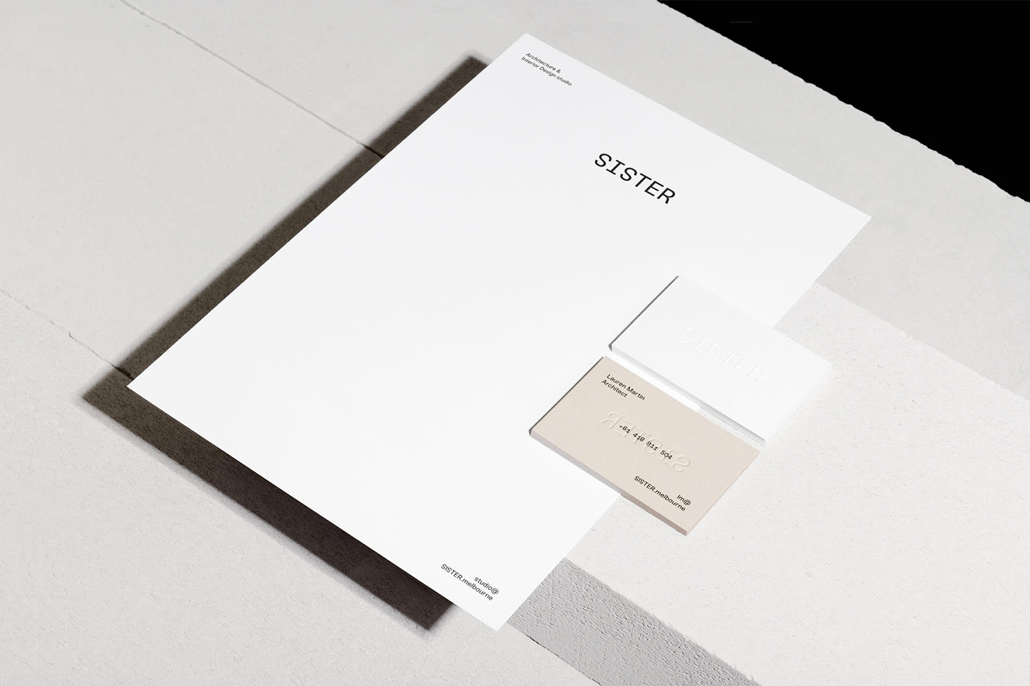 Minimalist brand identity stationery mockup featuring white letterhead and business cards with the Sister logo resting on a textured surface
