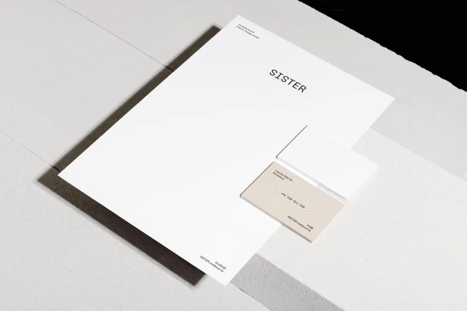 Minimalist brand identity stationery mockup featuring white letterhead and business cards with the Sister logo resting on a textured surface
