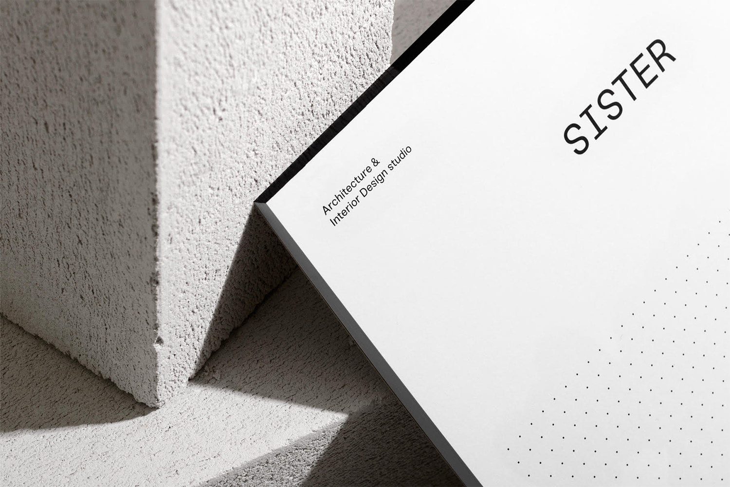 Minimalist graphic design brand identity presentation featuring Sister studio typography on white card leaning against textured concrete blocks.