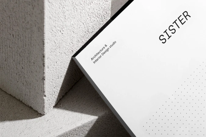 Minimalist graphic design brand identity presentation featuring Sister studio typography on white card leaning against textured concrete blocks.
