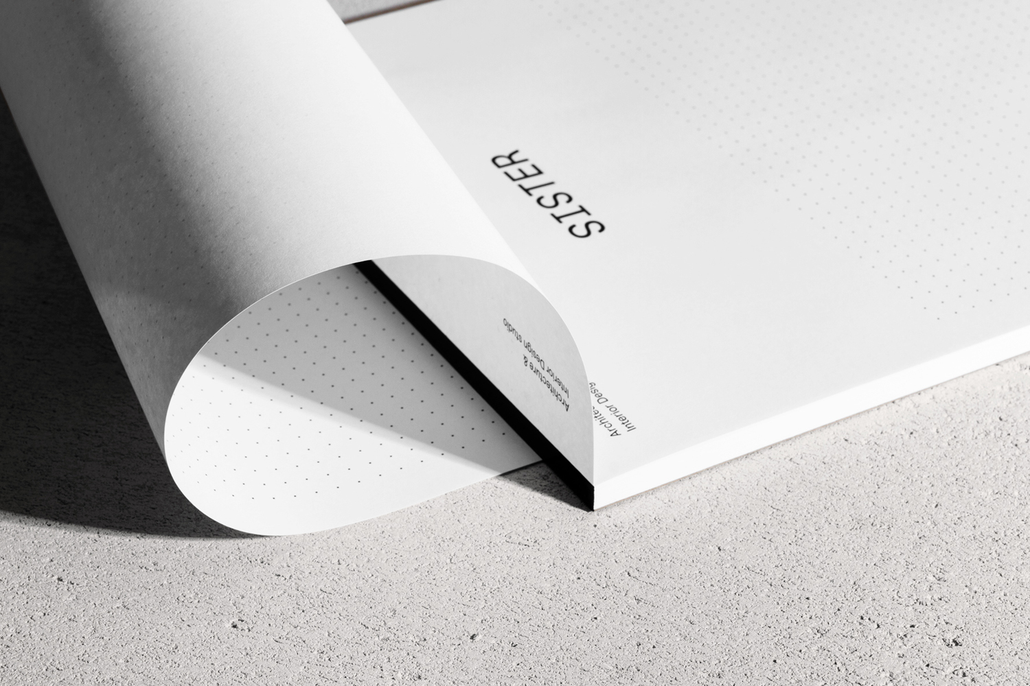Curved white dotted paper sheet with Sister brand typography resting on a grey textured surface.